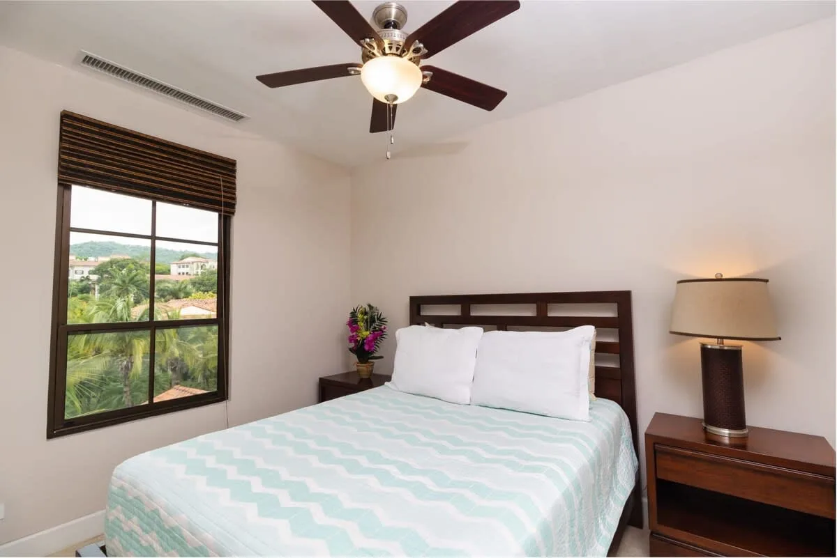 Un dormitorio con una cama, una ventana y una lámpara de mesita.