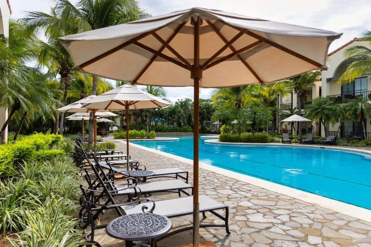 Zona común: Piscina al aire libre con asientos reclinables y sombrillas grandes.