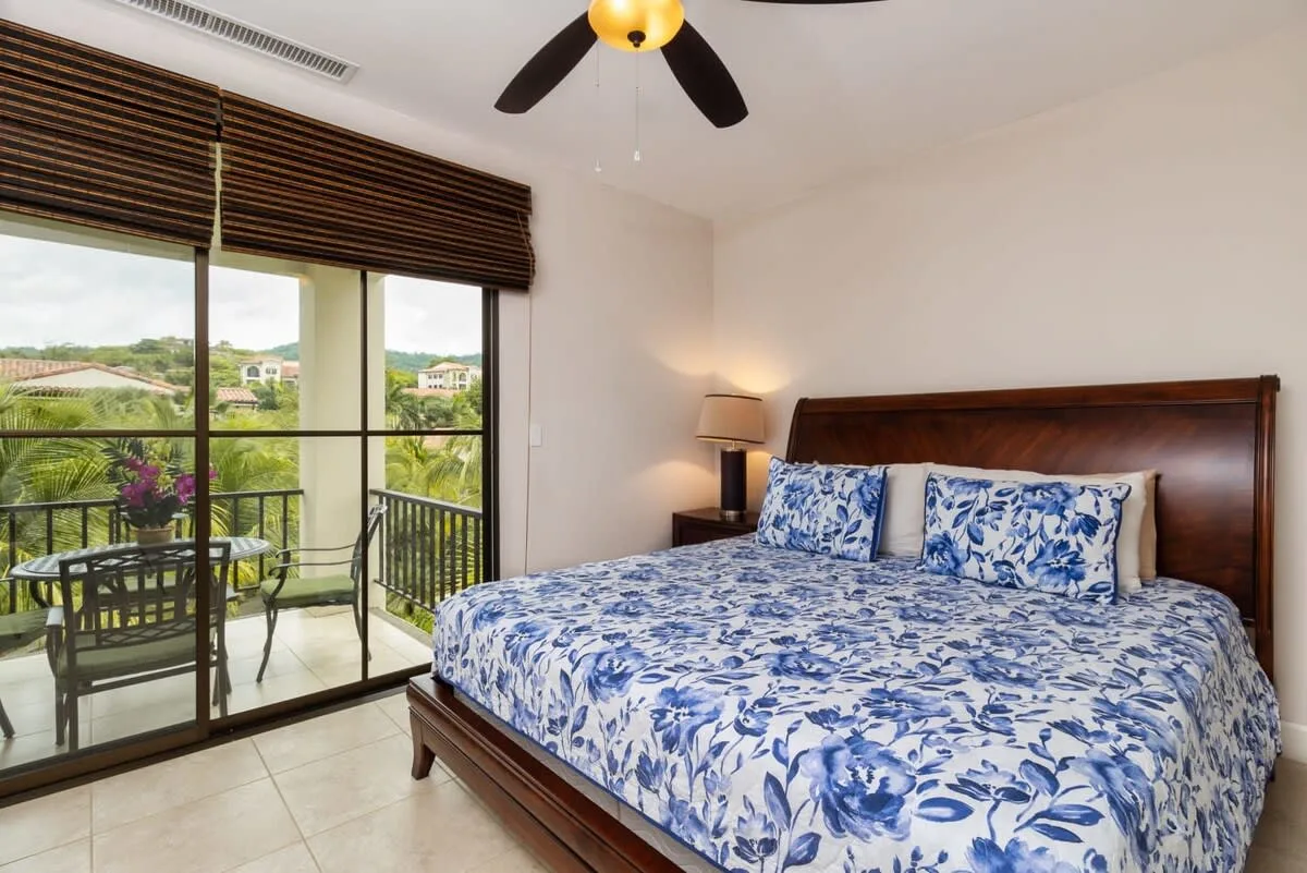 Un dormitorio con una cama estampada en azul y blanco junto a puertas corredizas de vidrio.