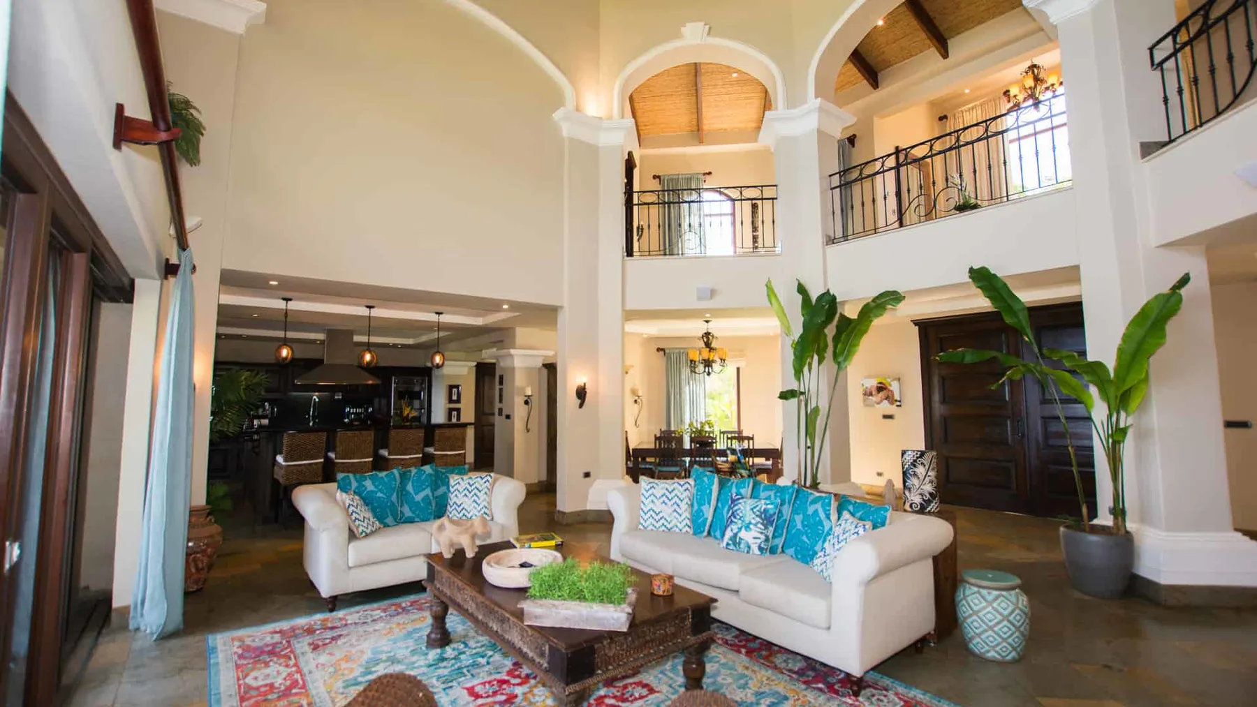 A spacious living room with light seating, a coffee table, and an open kitchen.
