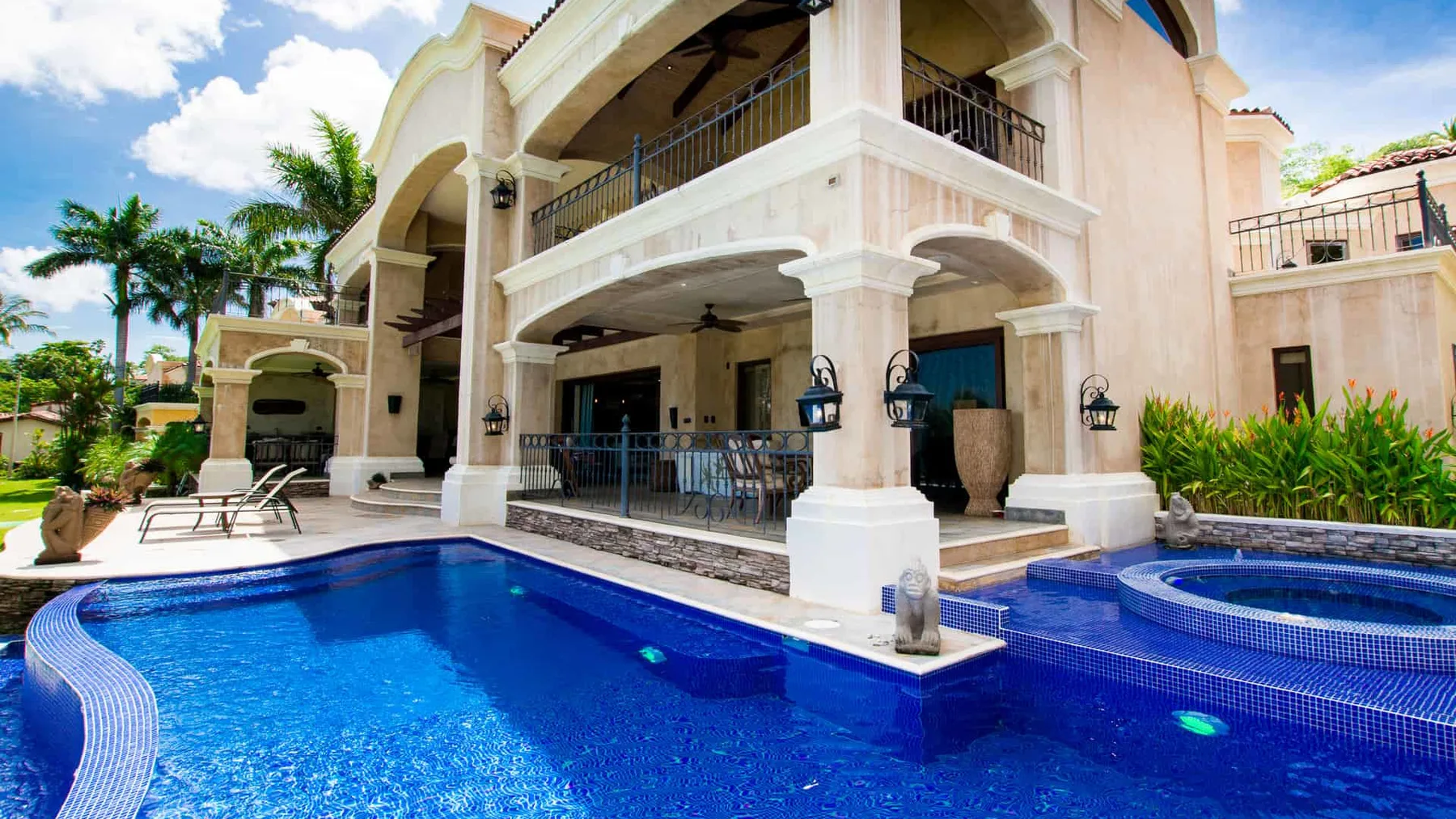 A large outdoor swimming pool sits beside a multi-story building with covered balconies.