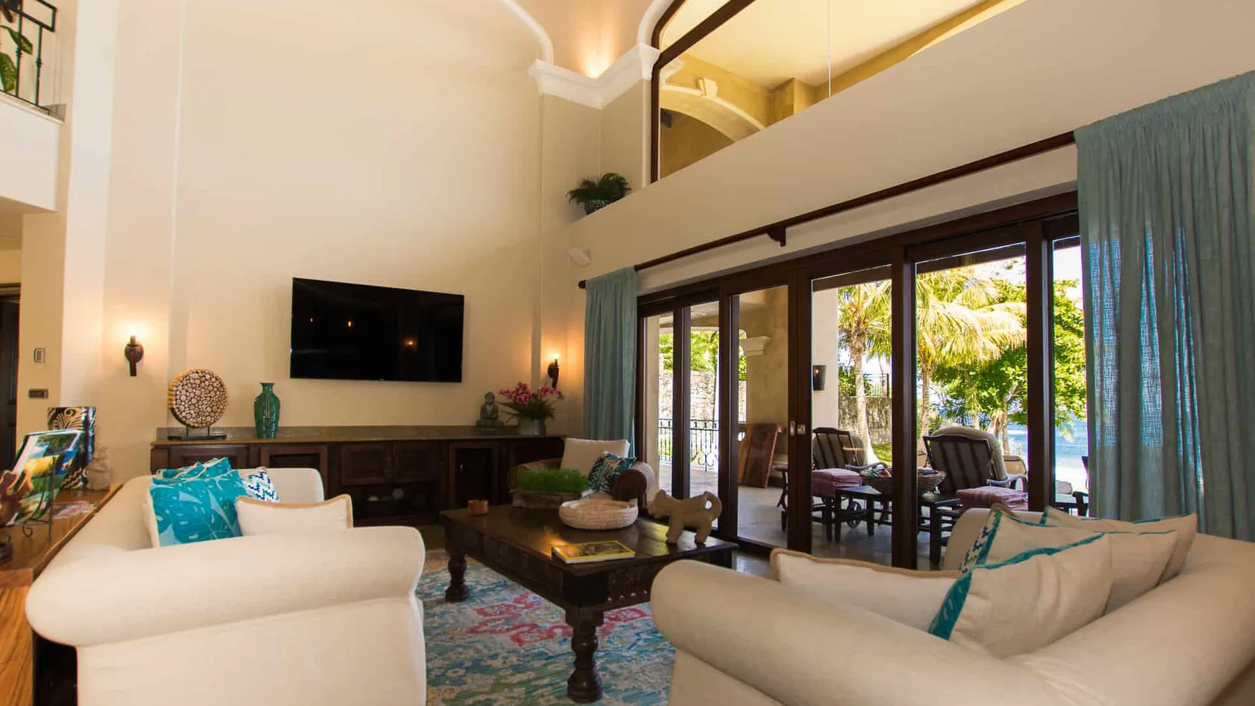A spacious living room with seating, a television, and glass doors opening onto a patio.