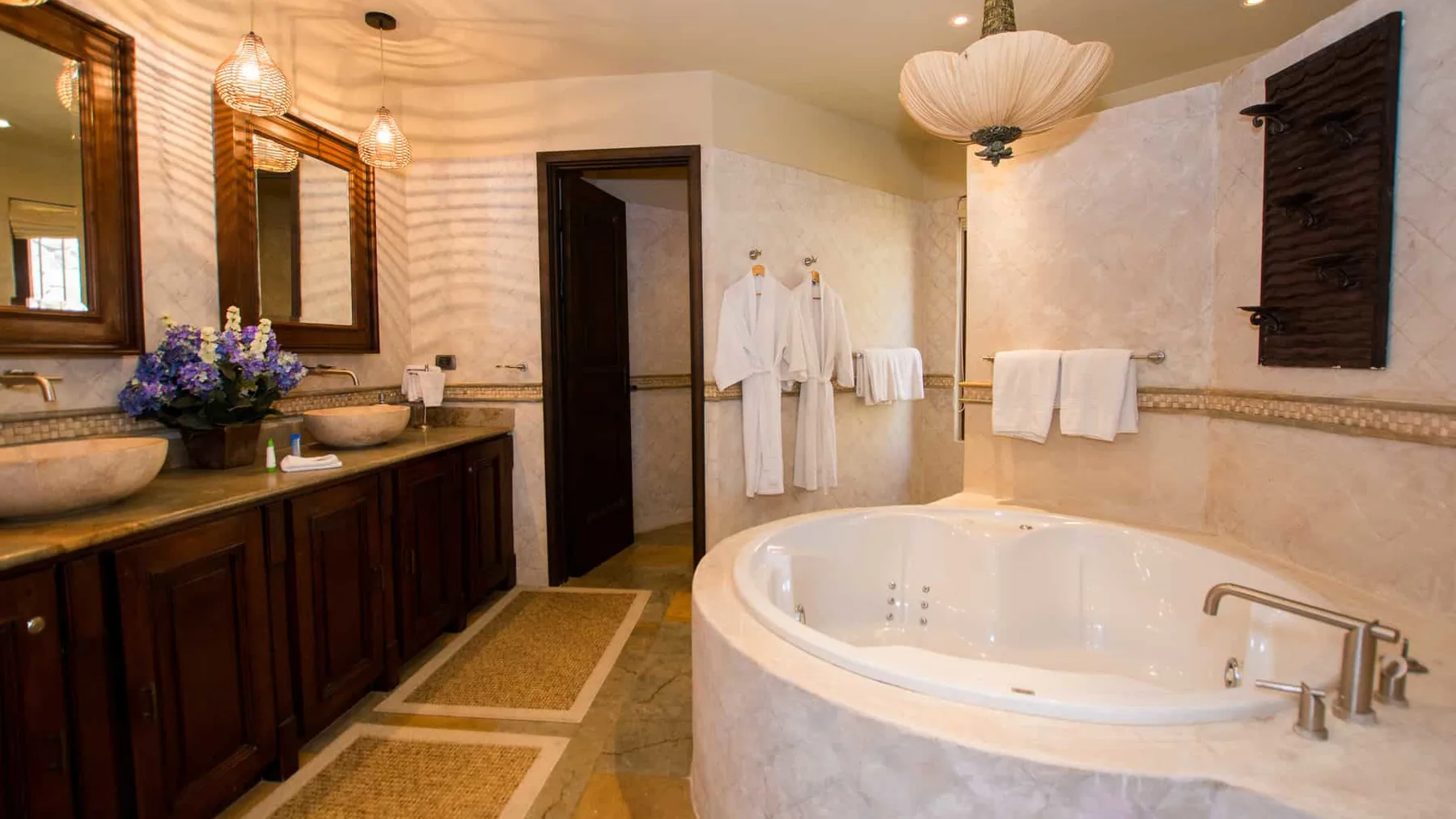 A spacious bathroom features a large soaking tub, double sinks, and hanging towels.