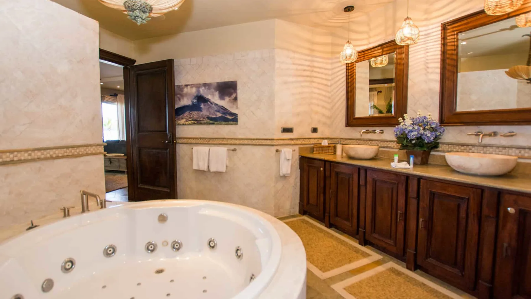 A bathroom with a large jetted tub and a long vanity beneath two mirrors.