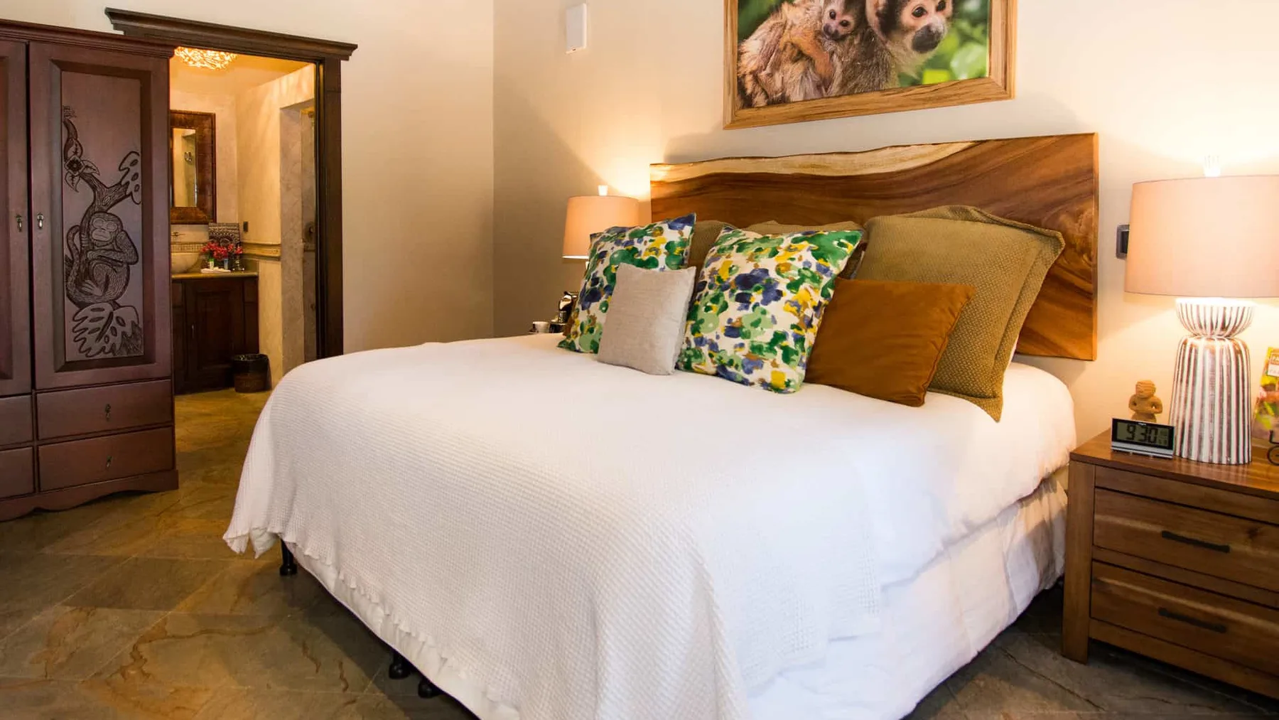 A bedroom with a large bed dressed in white bedding and colorful pillows.