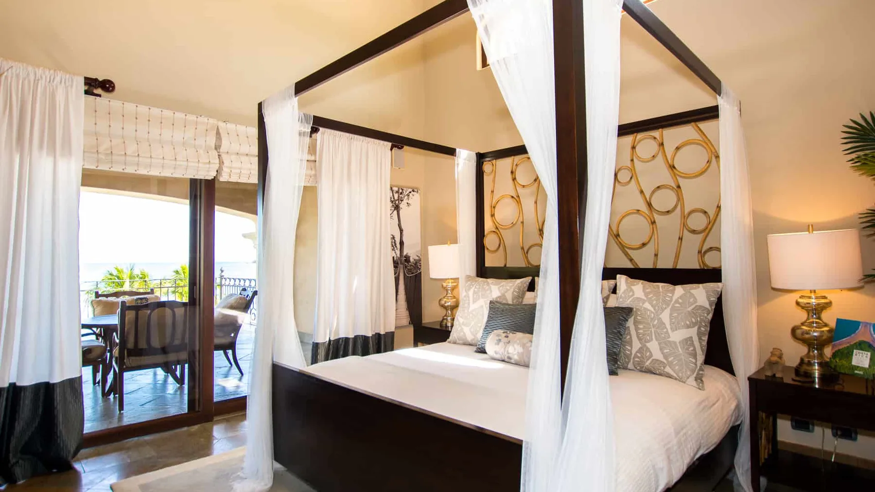 A bedroom with a canopy bed and glass doors opening to a balcony.