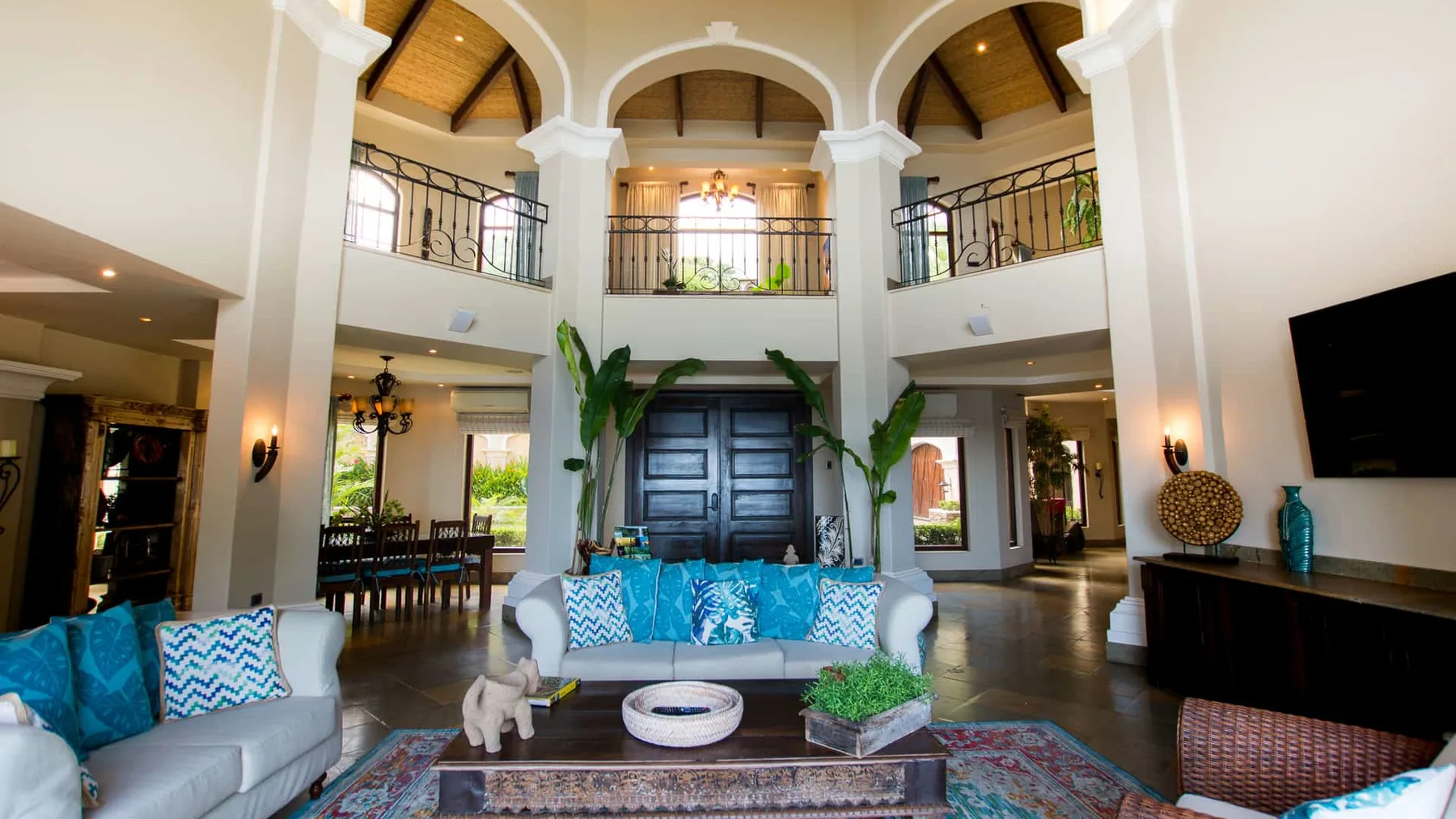 A spacious two-story living room has arched openings, a central entrance, and seating.