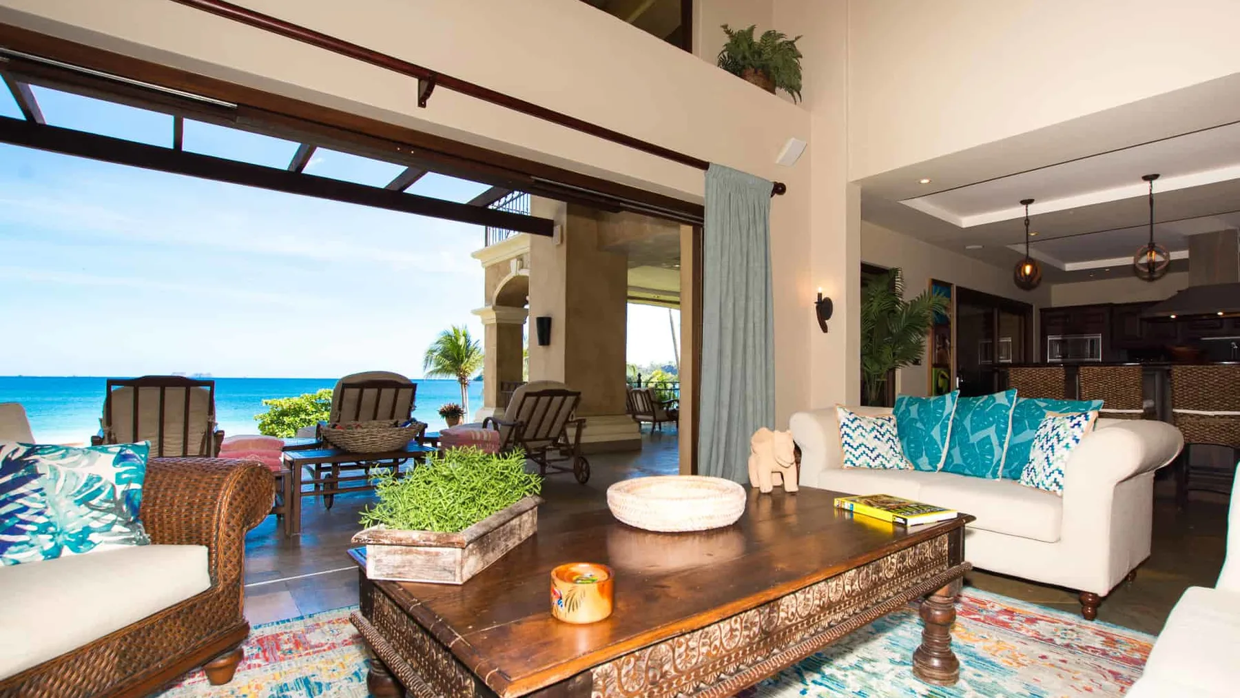 An open-plan living room with seating, a wooden coffee table, and a view of the sea.