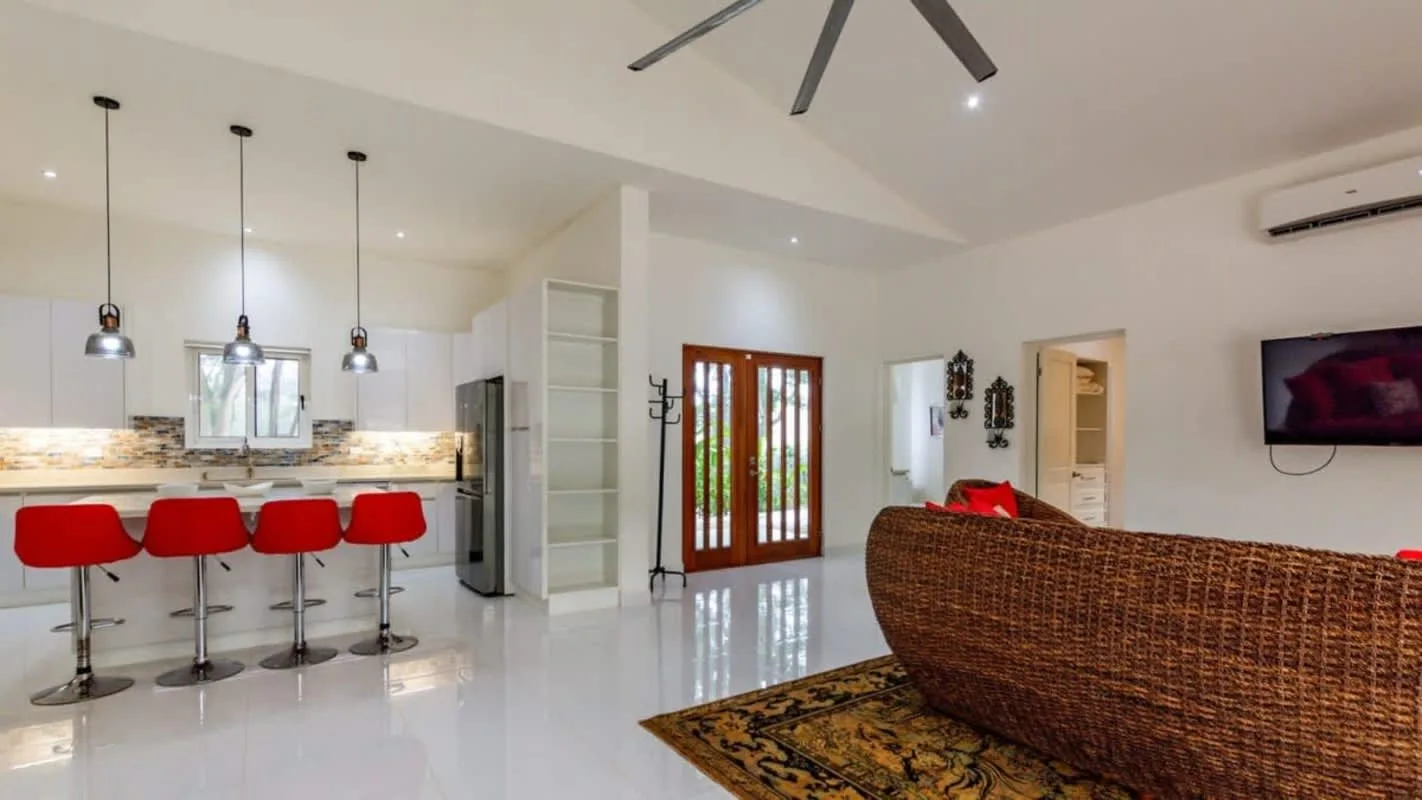 An open-plan living room and kitchen with a counter, seating, and glass doors.