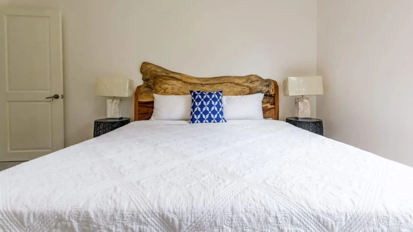 A bedroom with a large bed, white bedding, and a wood headboard.