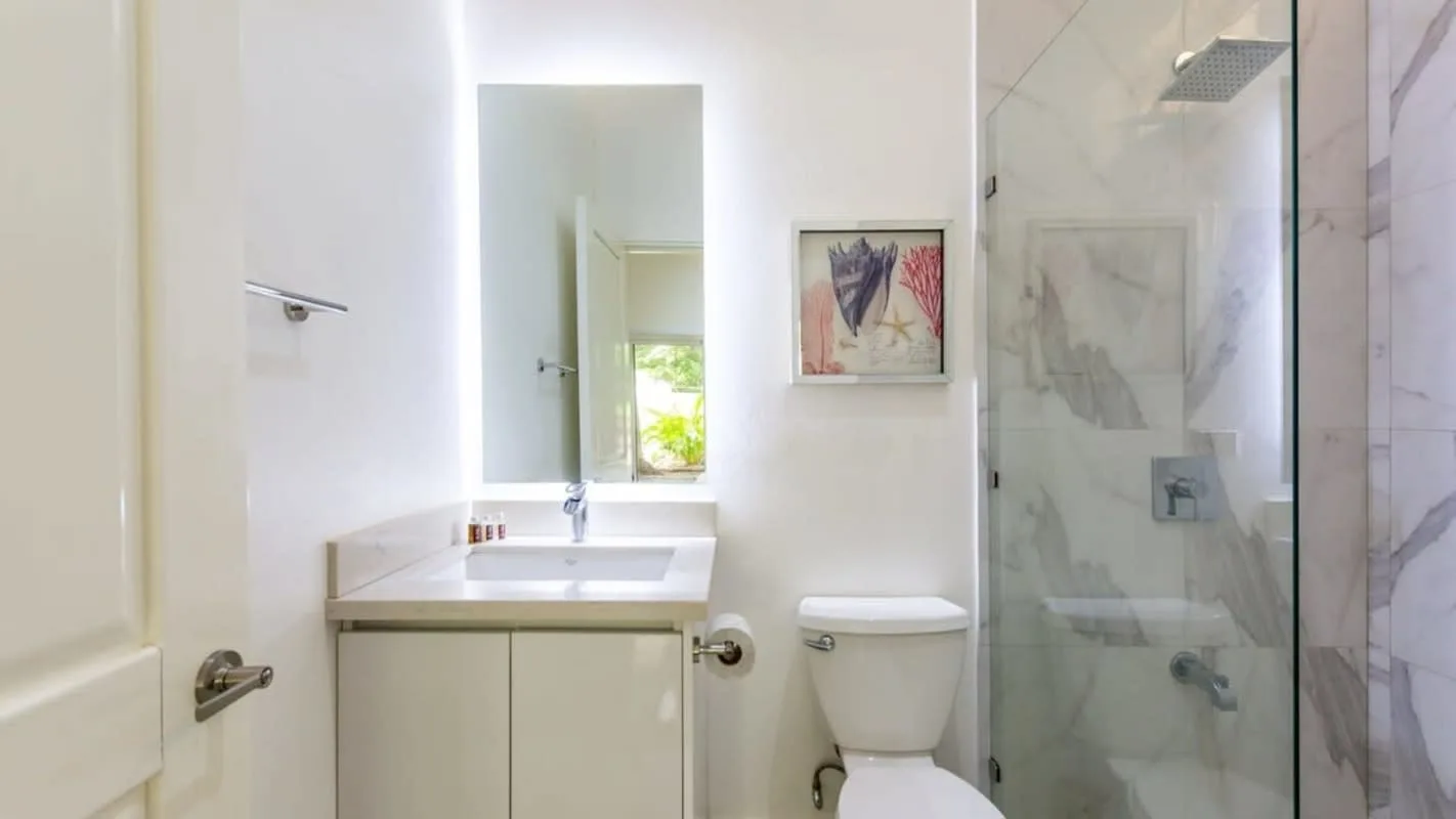 A bathroom with a vanity, toilet, and glass shower.