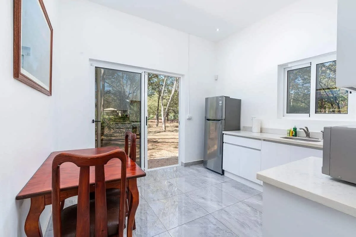 A bright kitchen and dining area with a table beside sliding glass doors.