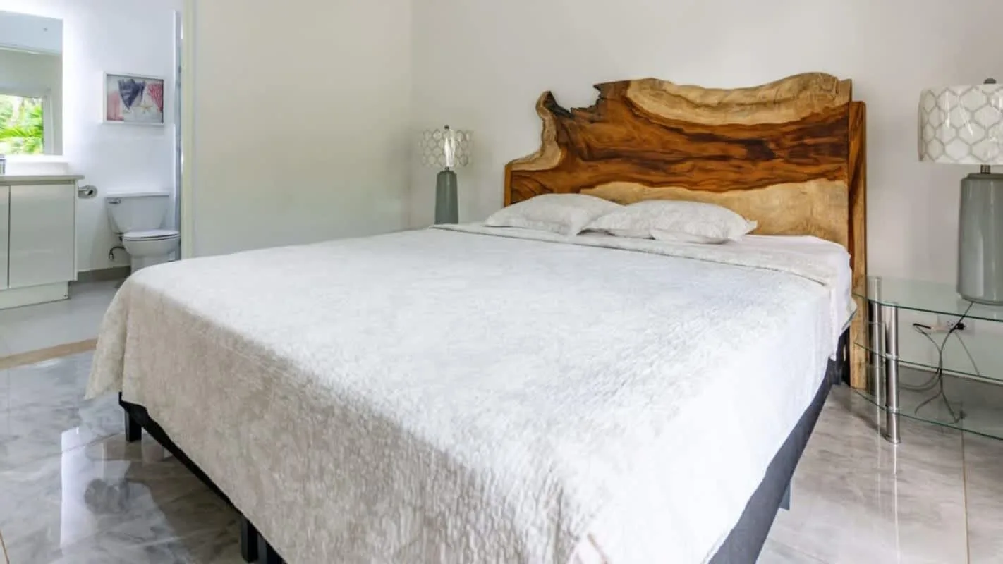 A bedroom with a large bed and a natural wood headboard.