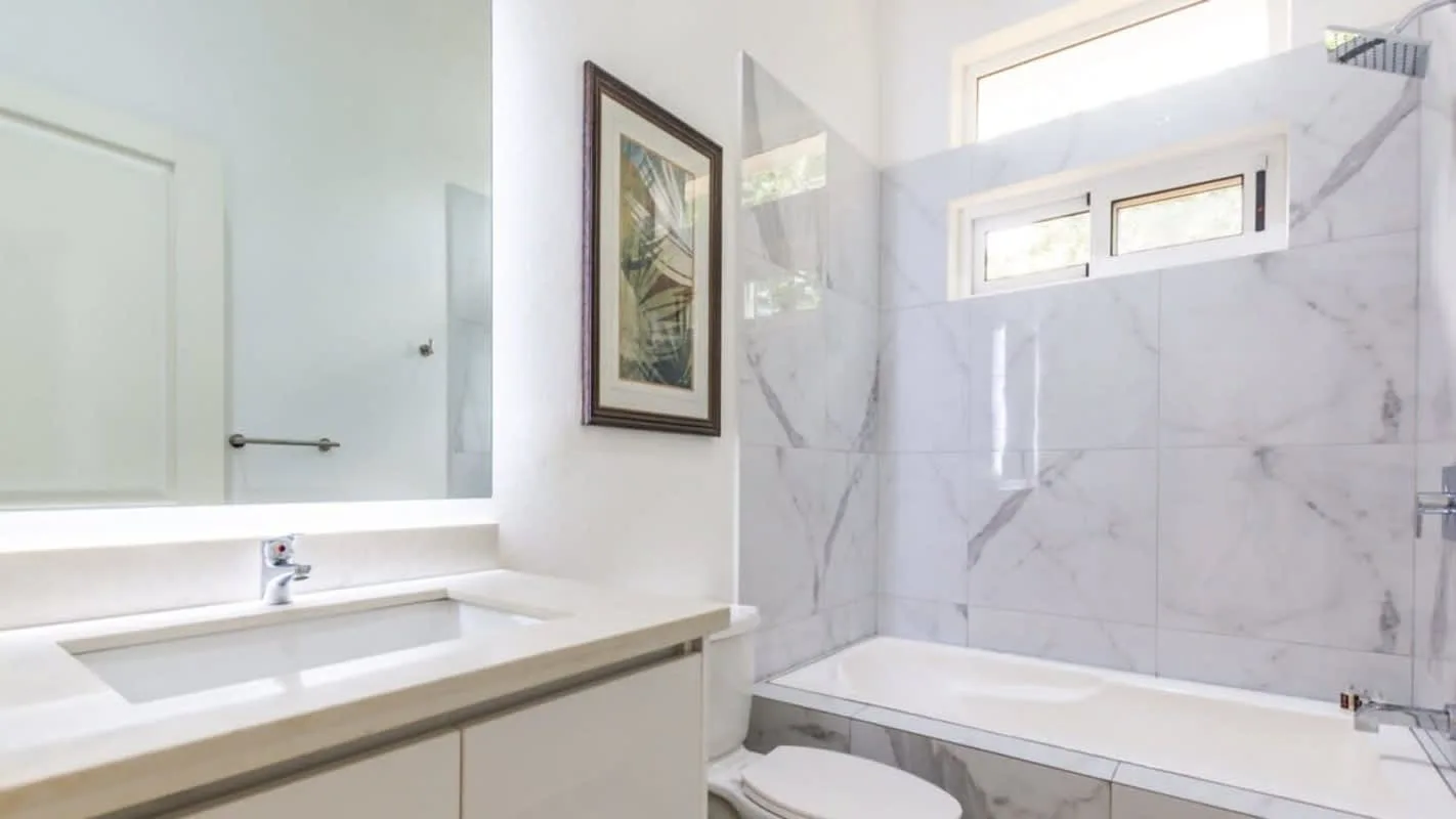 A bright bathroom with a bathtub, sink, and framed wall art.