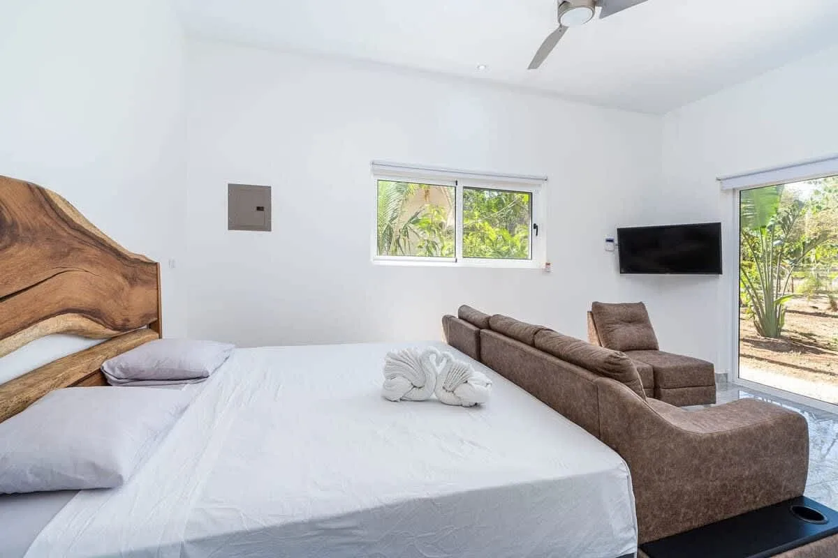 A bedroom with a large bed and a seating area beside the window.