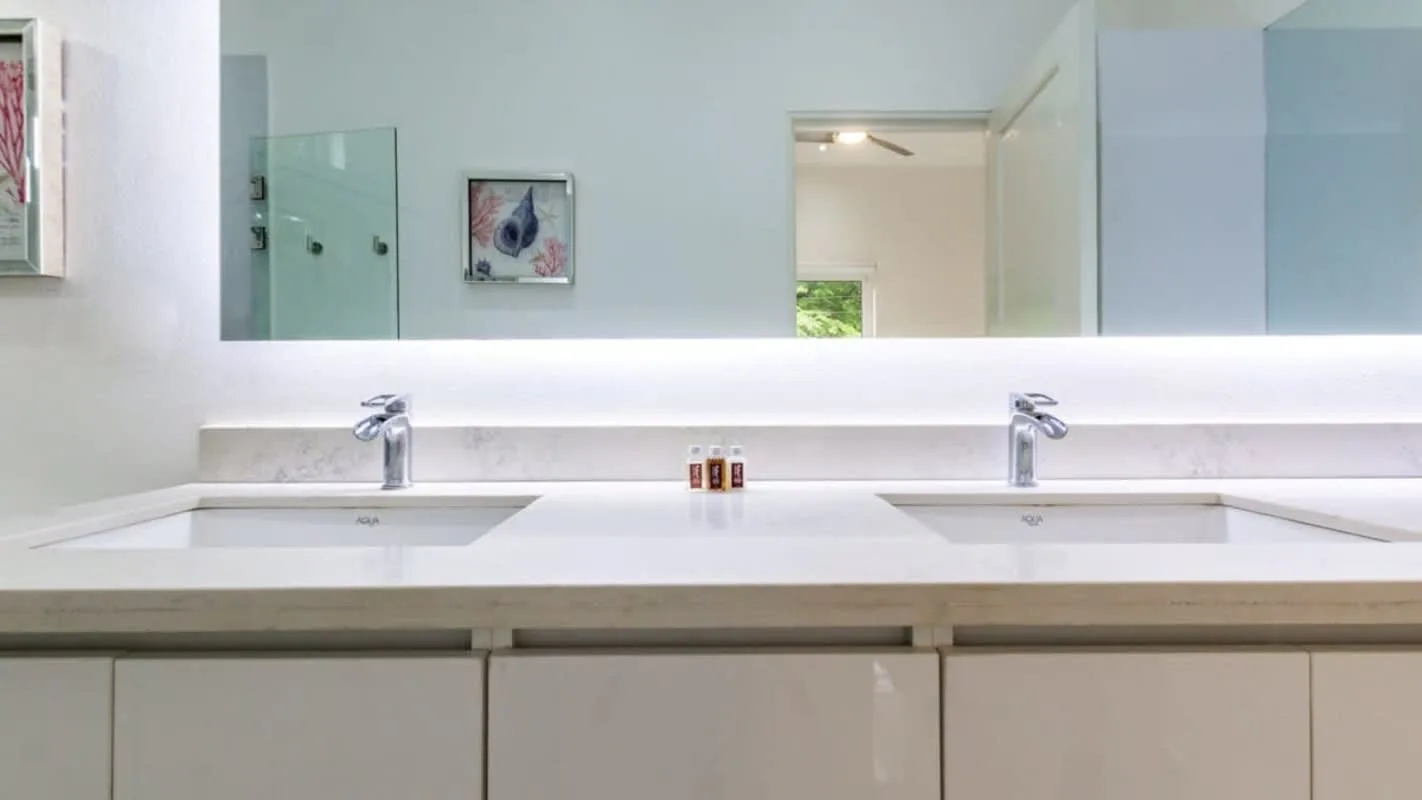 A bathroom vanity with two sinks sits beneath a wide wall mirror.