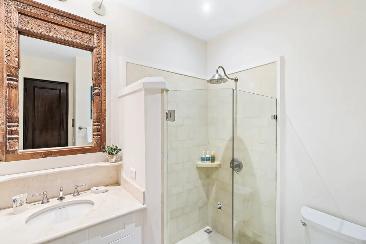 Un baño con ducha de vidrio, lavabo y espejo.