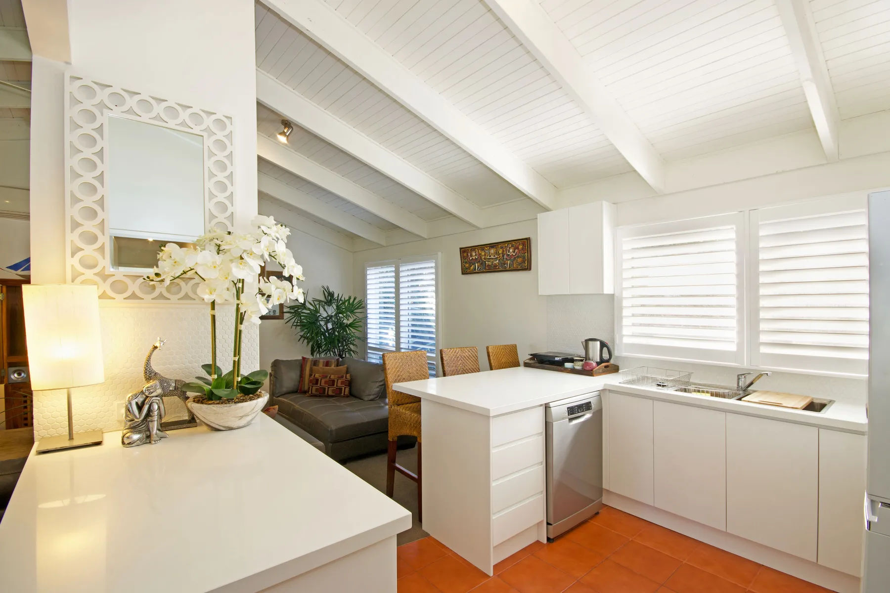 A bright kitchen with white cabinets, a central island, and shuttered windows.