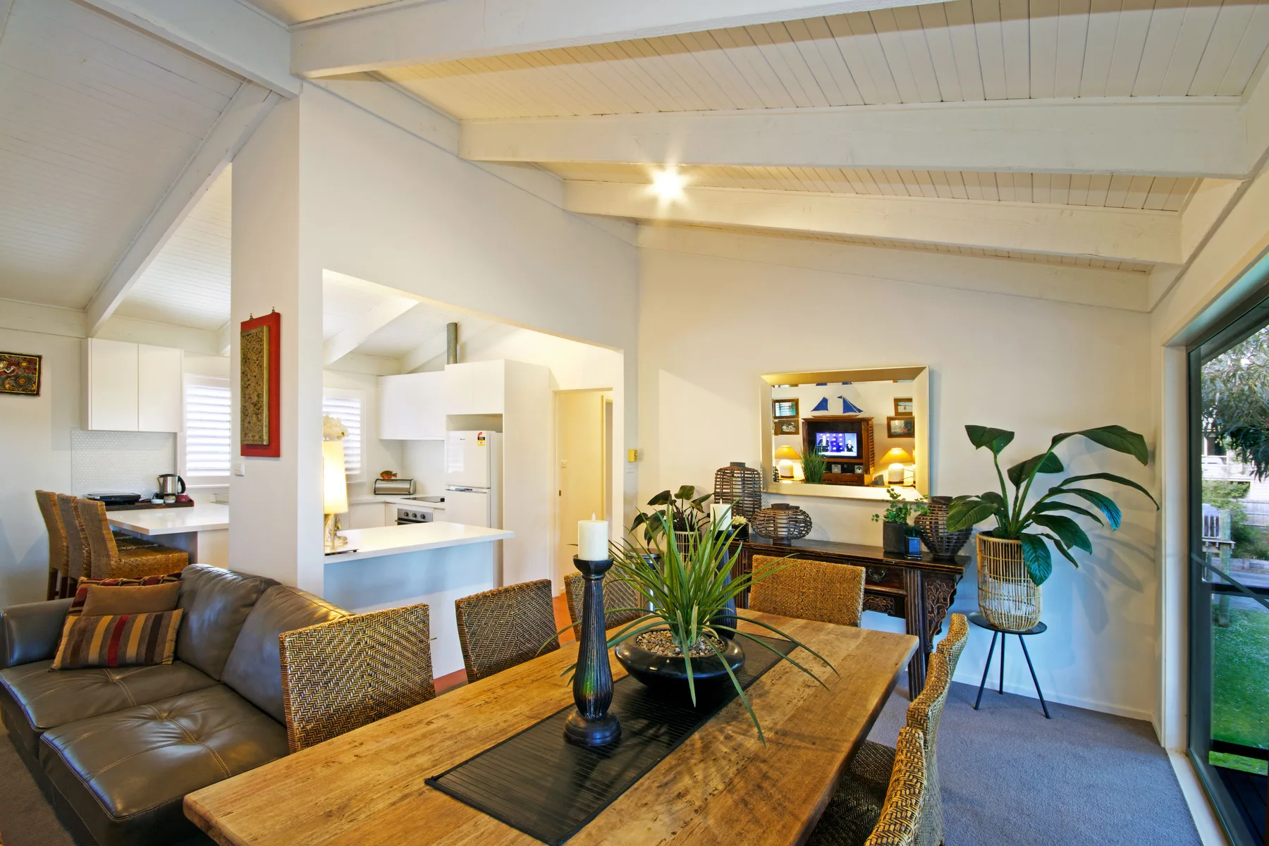 An open-plan living and dining area has a wooden table and a kitchen beyond.