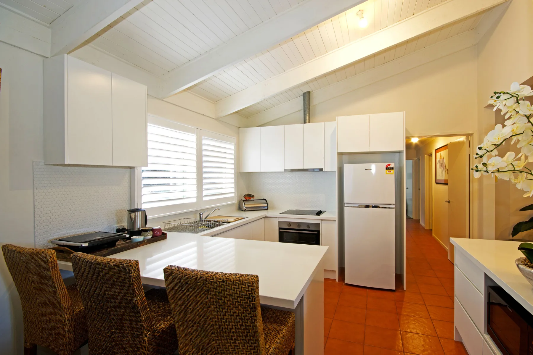 A bright kitchen with a central island, white cabinets, and windows overlooking the counter.