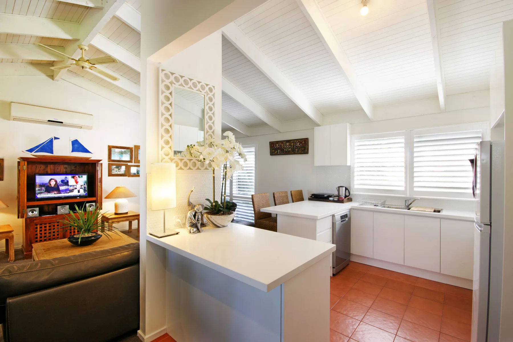 An open-plan kitchen and living area with a white island and seating.