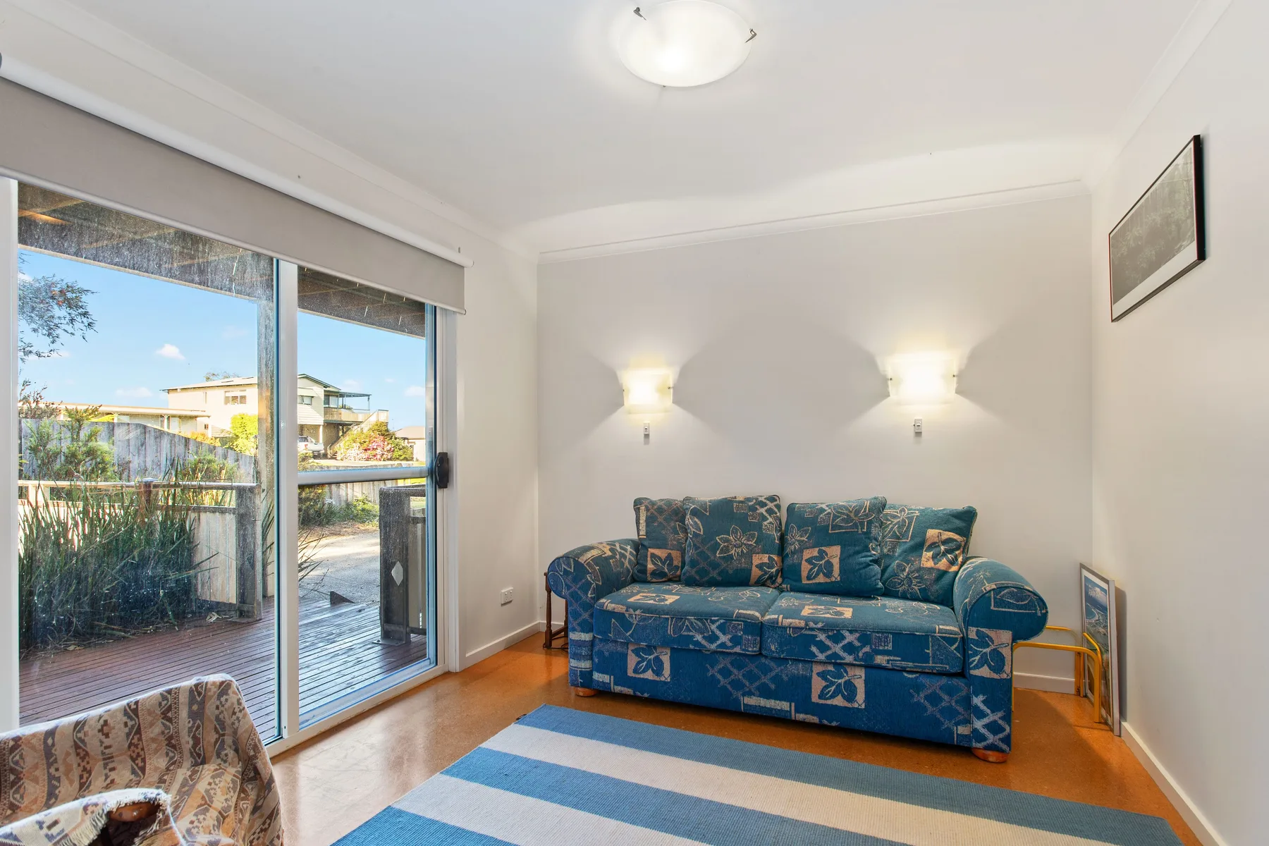 Una sala de estar con asientos azules junto a una puerta de vidrio y ventanas.