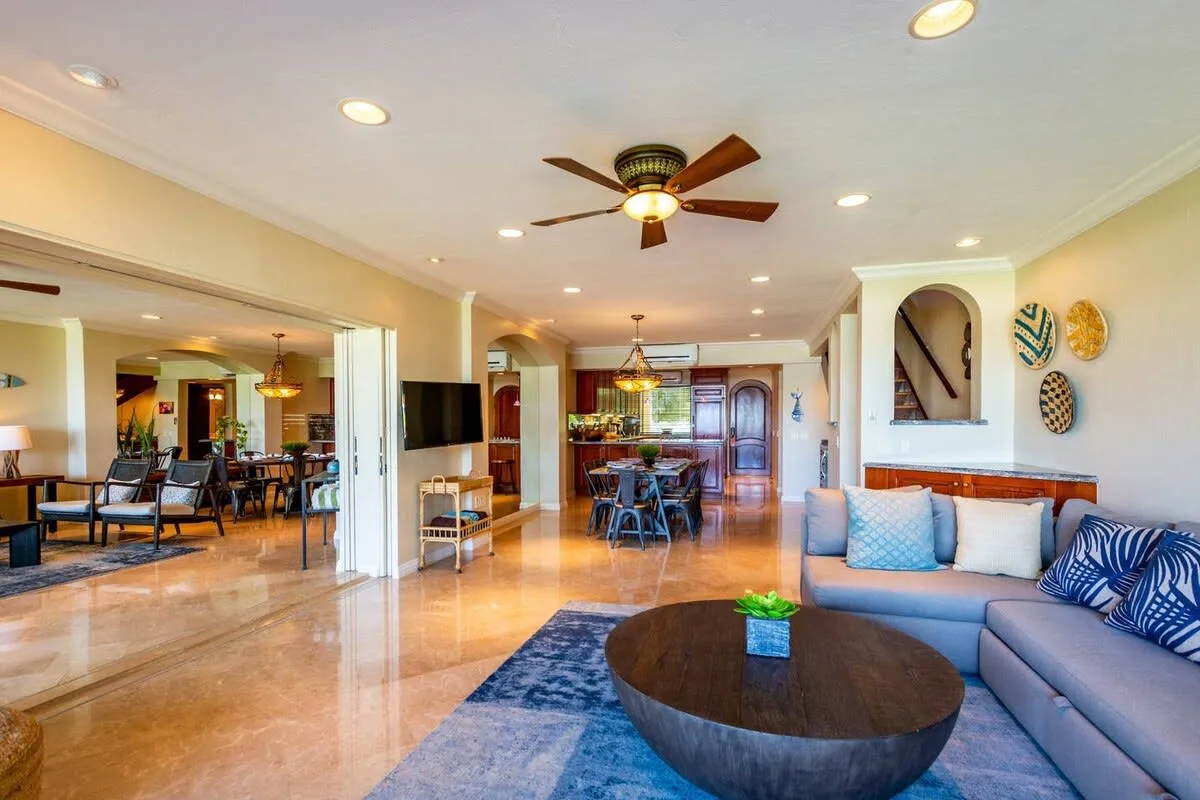 An open living and dining area with seating, a ceiling fan, and a round coffee table.