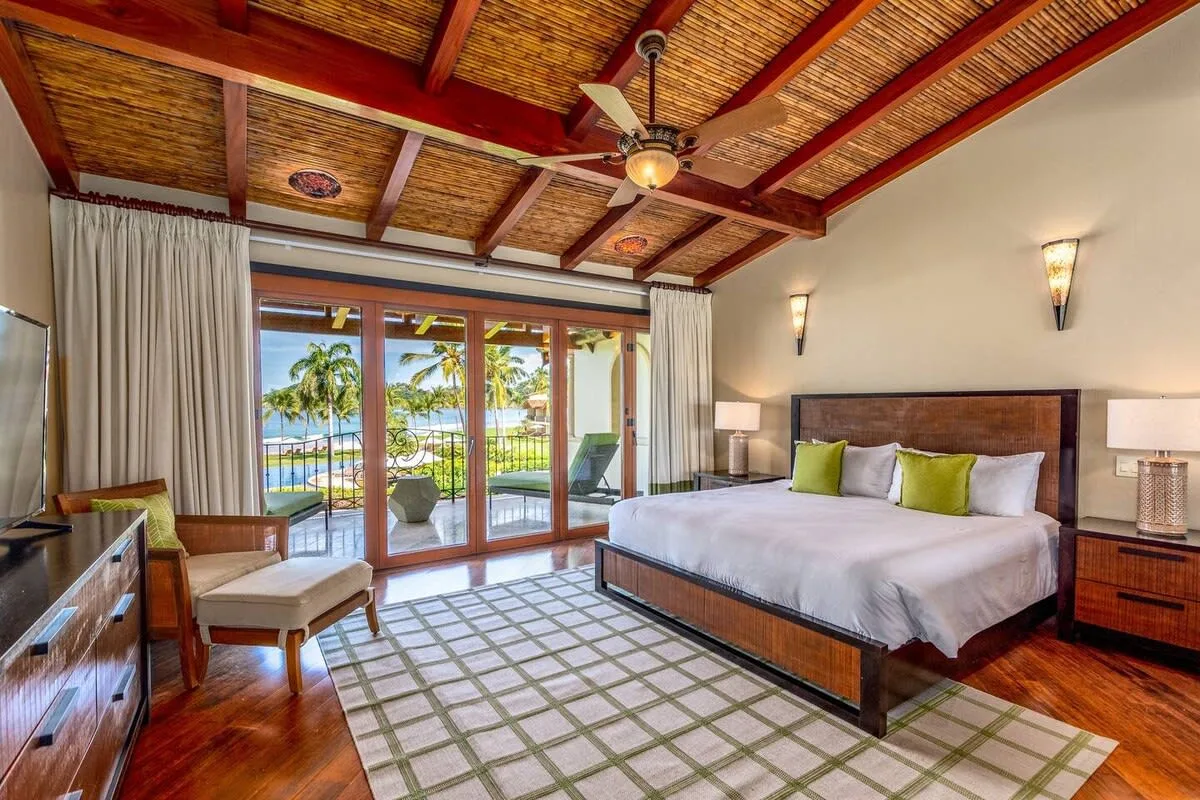 A bedroom with a large bed and glass doors opening onto a balcony.