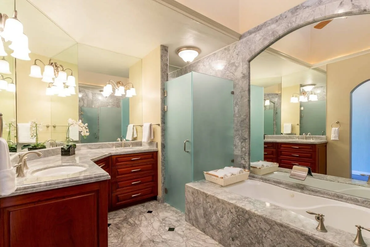 A bathroom with a glass shower, wooden vanities, and a large mirror.