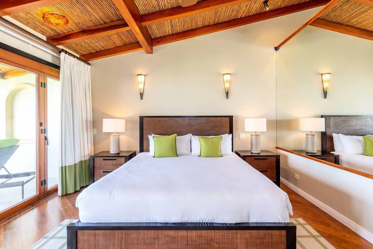 A bedroom with a bed, matching bedside lamps, and a mirrored wall.