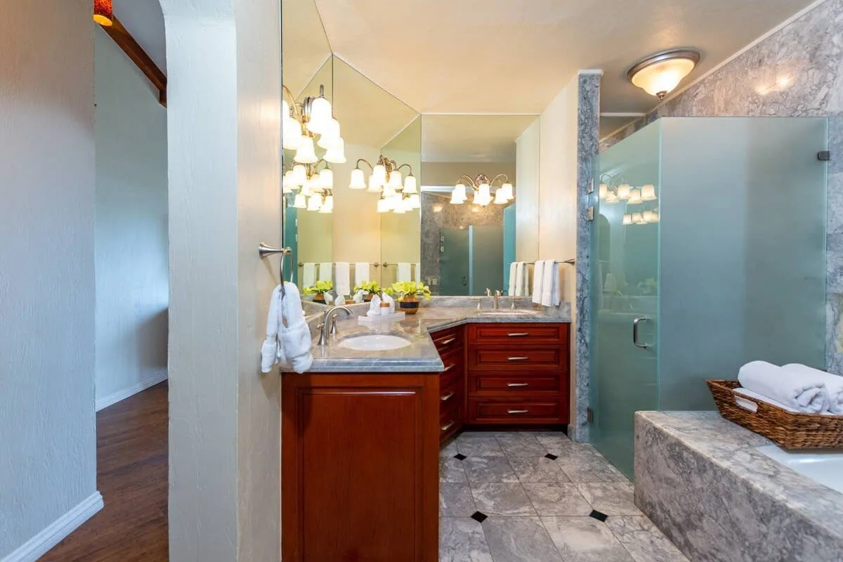 A bathroom with a wood vanity, wide mirror, and glass shower.