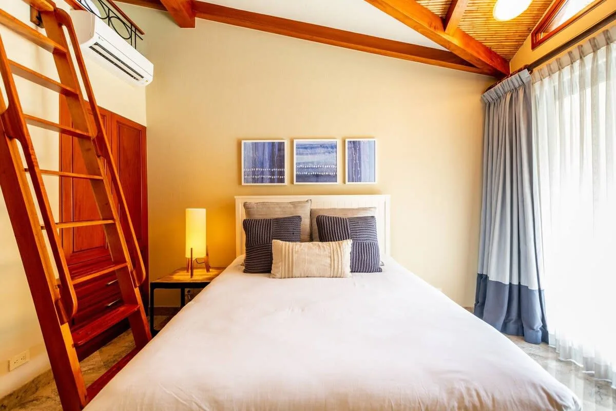 A bedroom with a large bed, bedside lamp, and curtains.