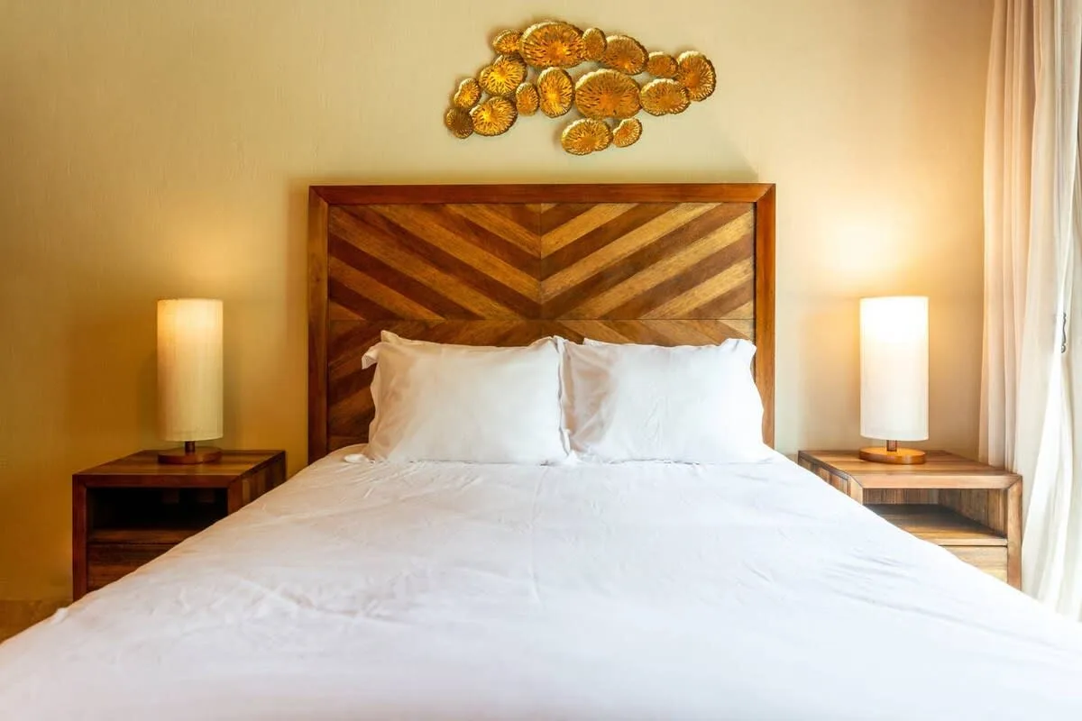 A bedroom with a bed, patterned wooden headboard, and matching bedside tables.