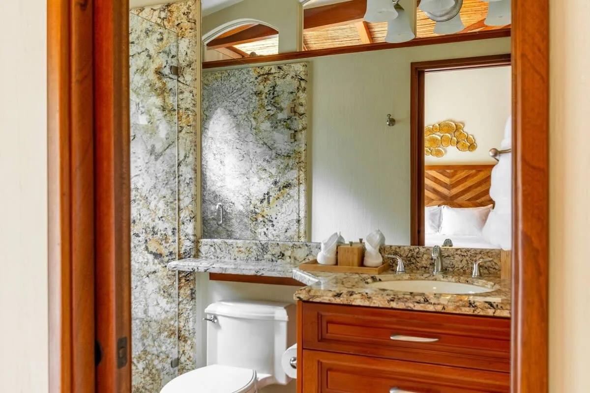 A bathroom with a stone-patterned vanity, mirror, and toilet.