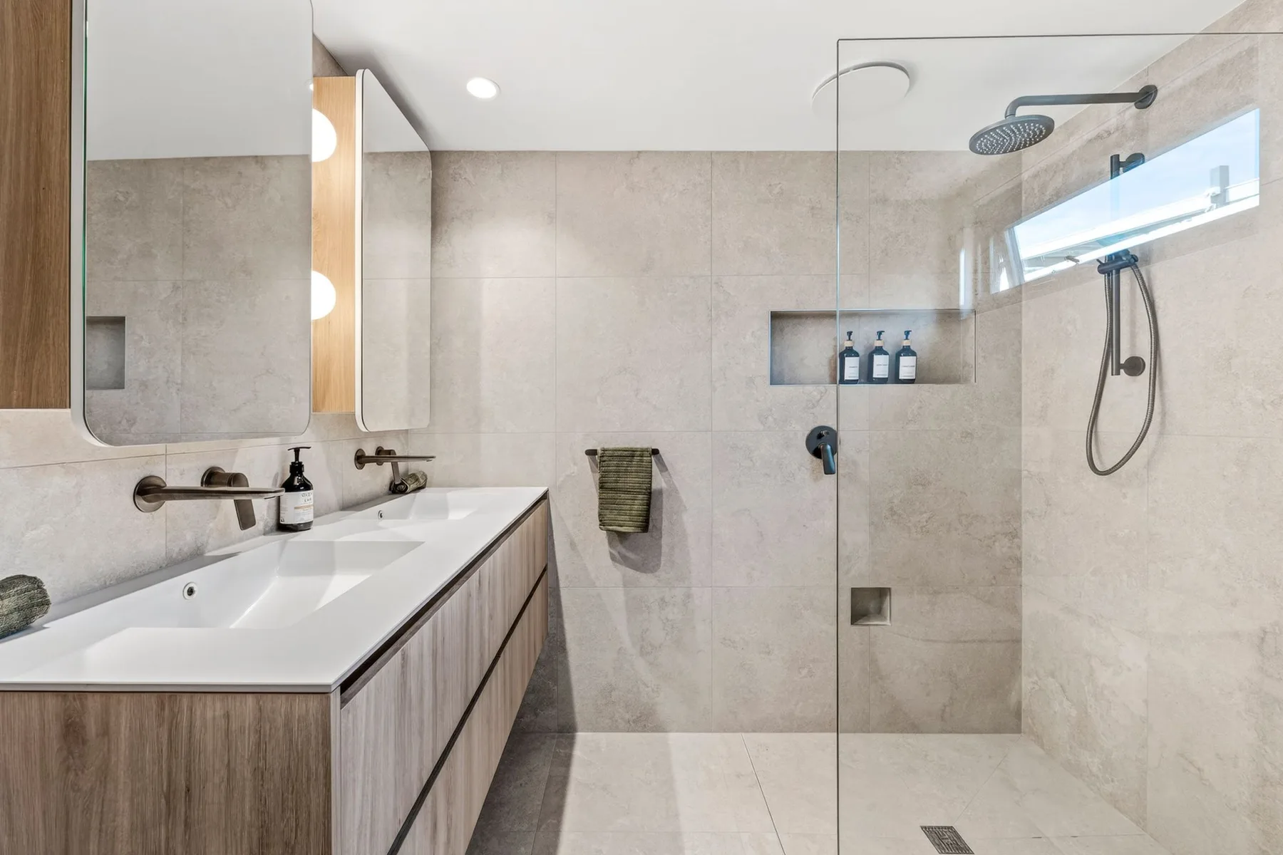 Un baño luminoso con azulejos, lavabo y ducha de vidrio.