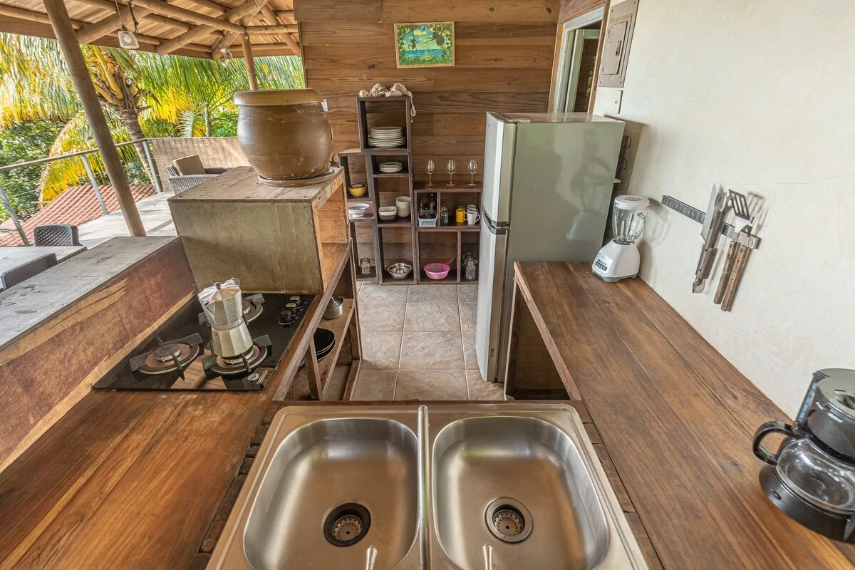 Una cocina exterior cubierta con encimeras de madera, un fregadero doble y electrodomésticos.