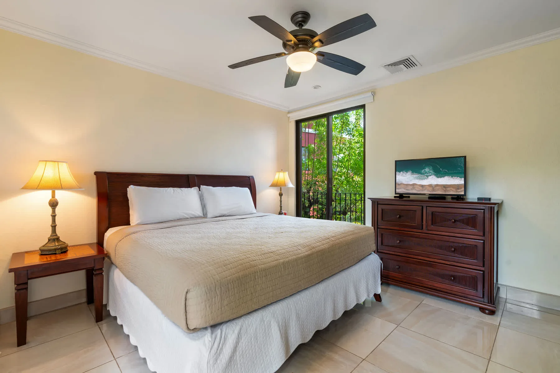 A bedroom with a neatly made bed, bedside lamps, and a dresser.