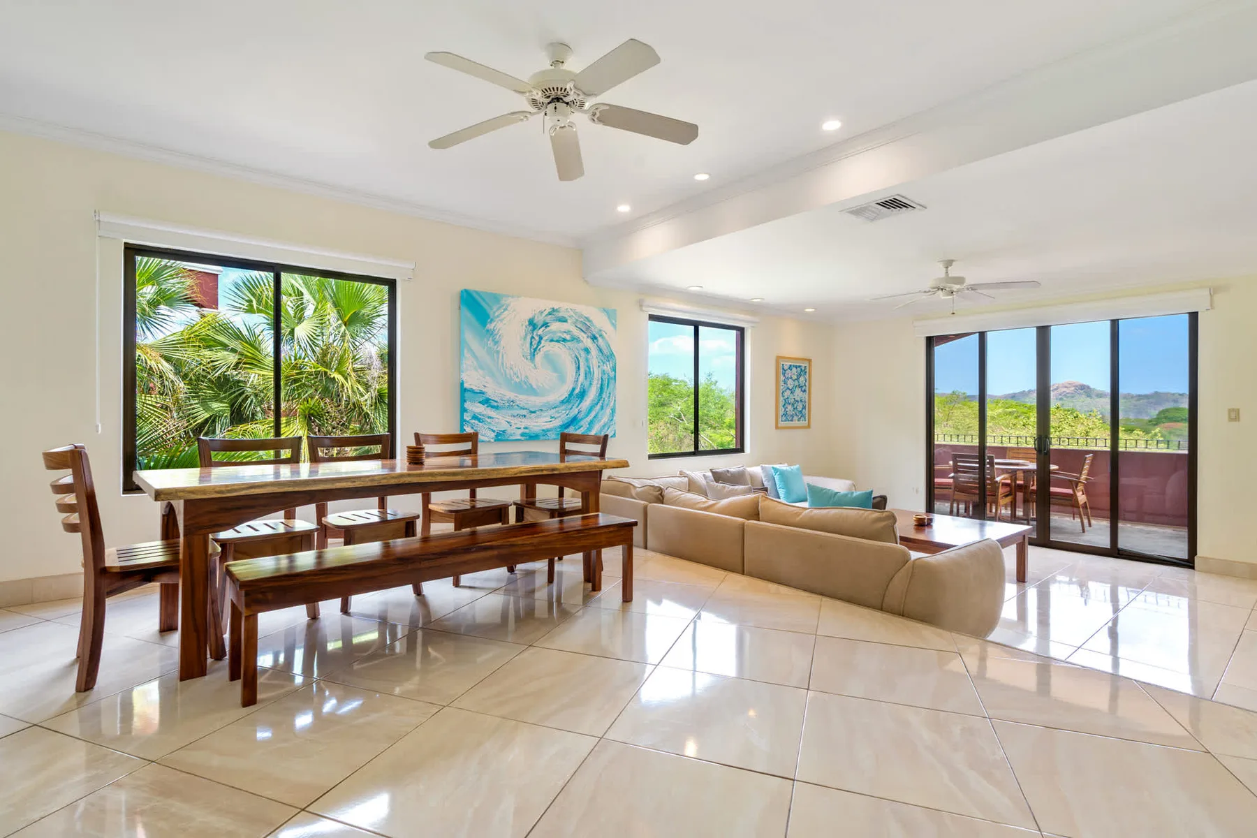 A bright open-plan living and dining room with large windows and seating.