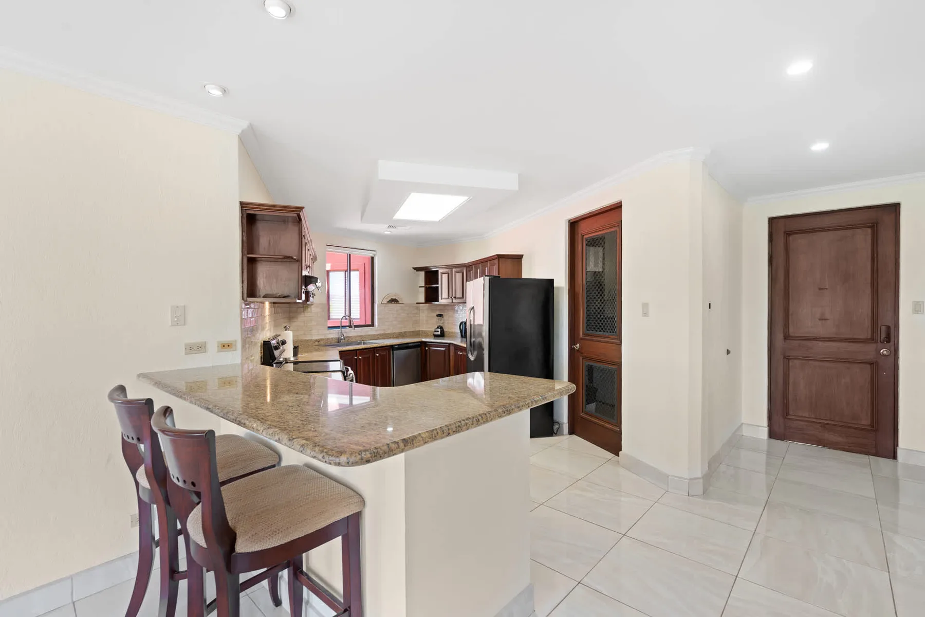 A kitchen with a large stone island and bar seating.