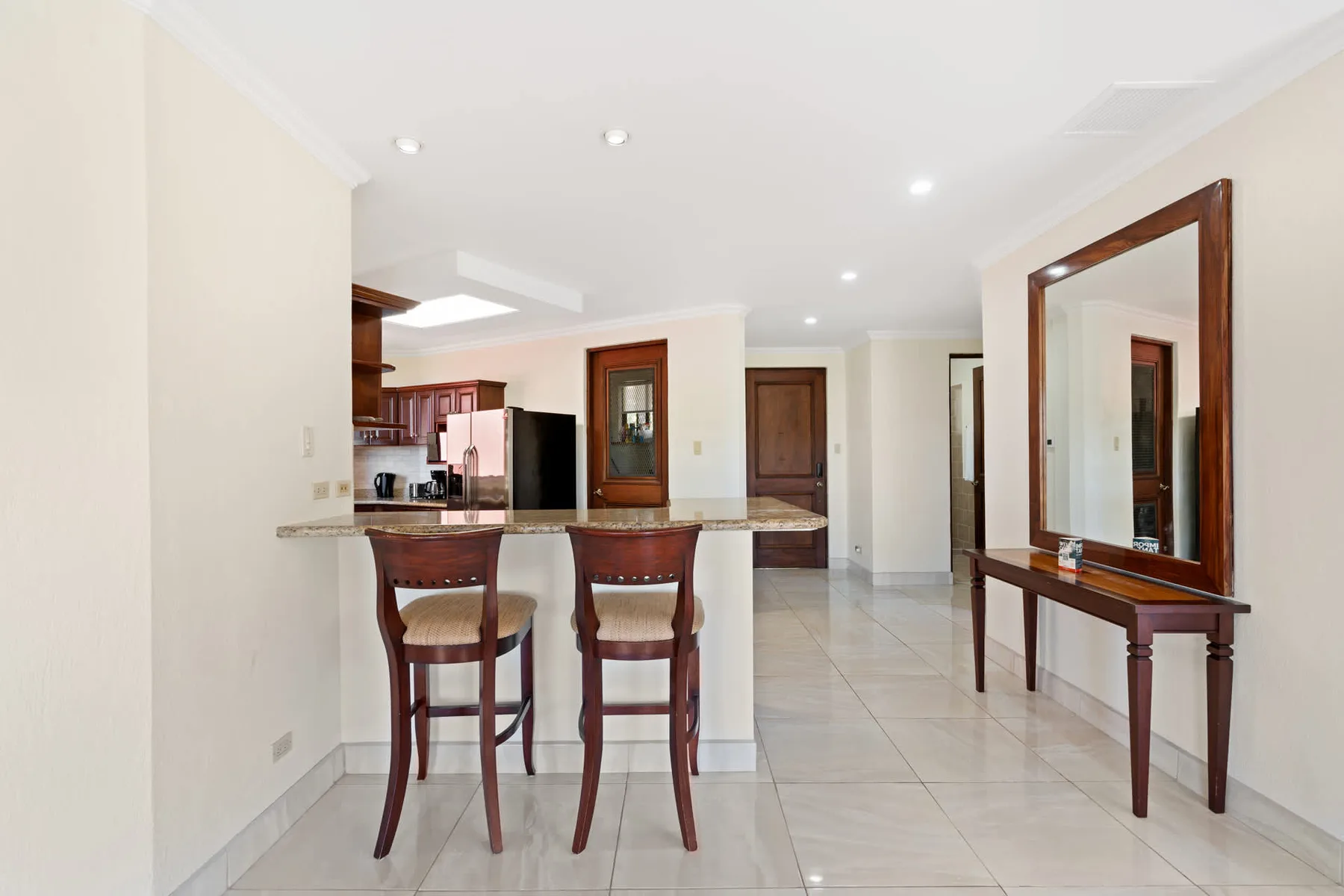 An open kitchen and dining area with a breakfast counter and a large wall mirror.