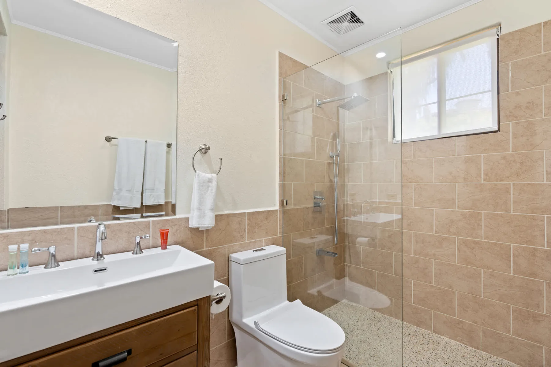 A bathroom with a vanity, toilet, and glass-enclosed shower.