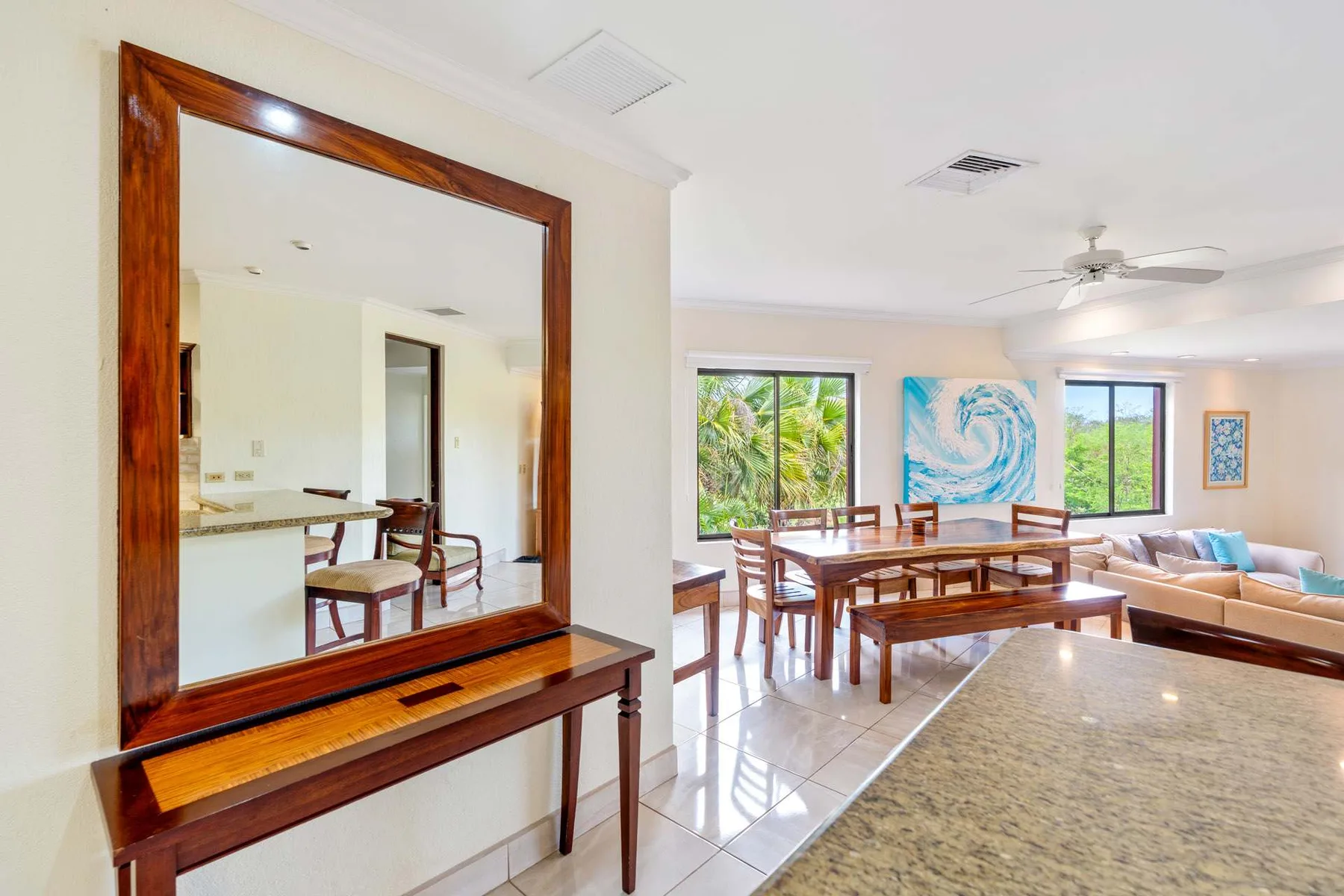 A bright living and dining area with a wooden table and large windows.