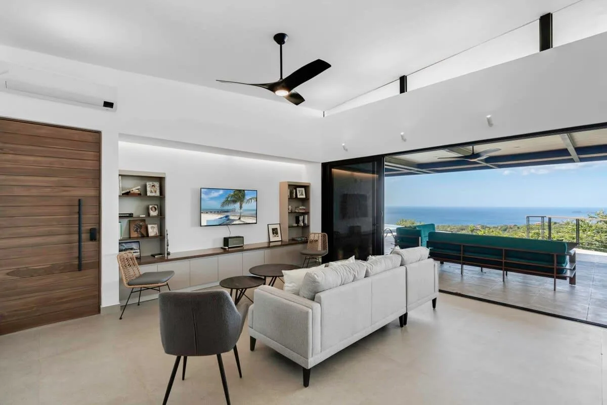 A bright living room opens onto a balcony with ocean views.