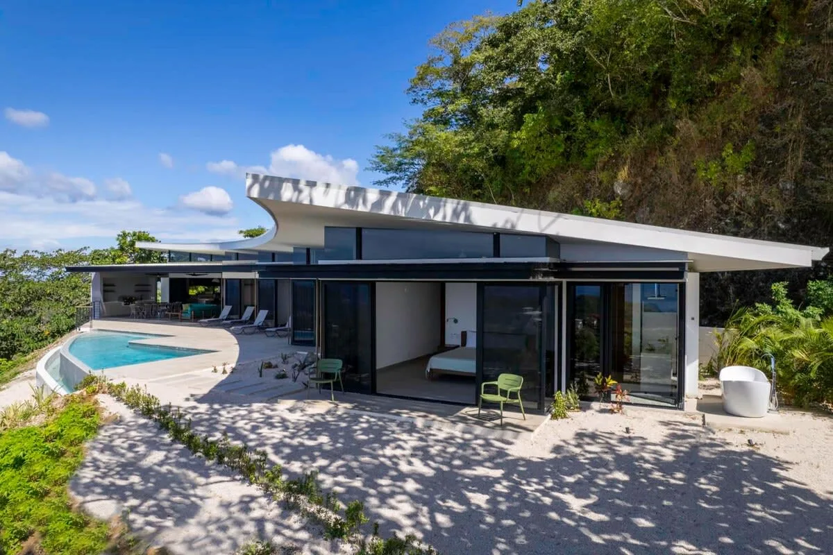 A modern house with a swimming pool and a shaded outdoor patio.
