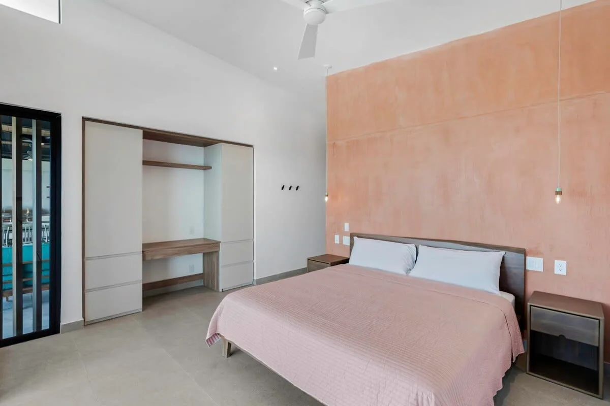 A bedroom with a bed, open shelving, and a sliding glass door.
