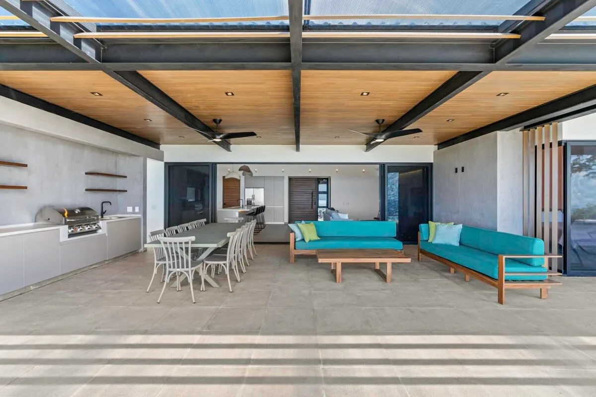 An open-plan living and dining area has turquoise seating and a long dining table.