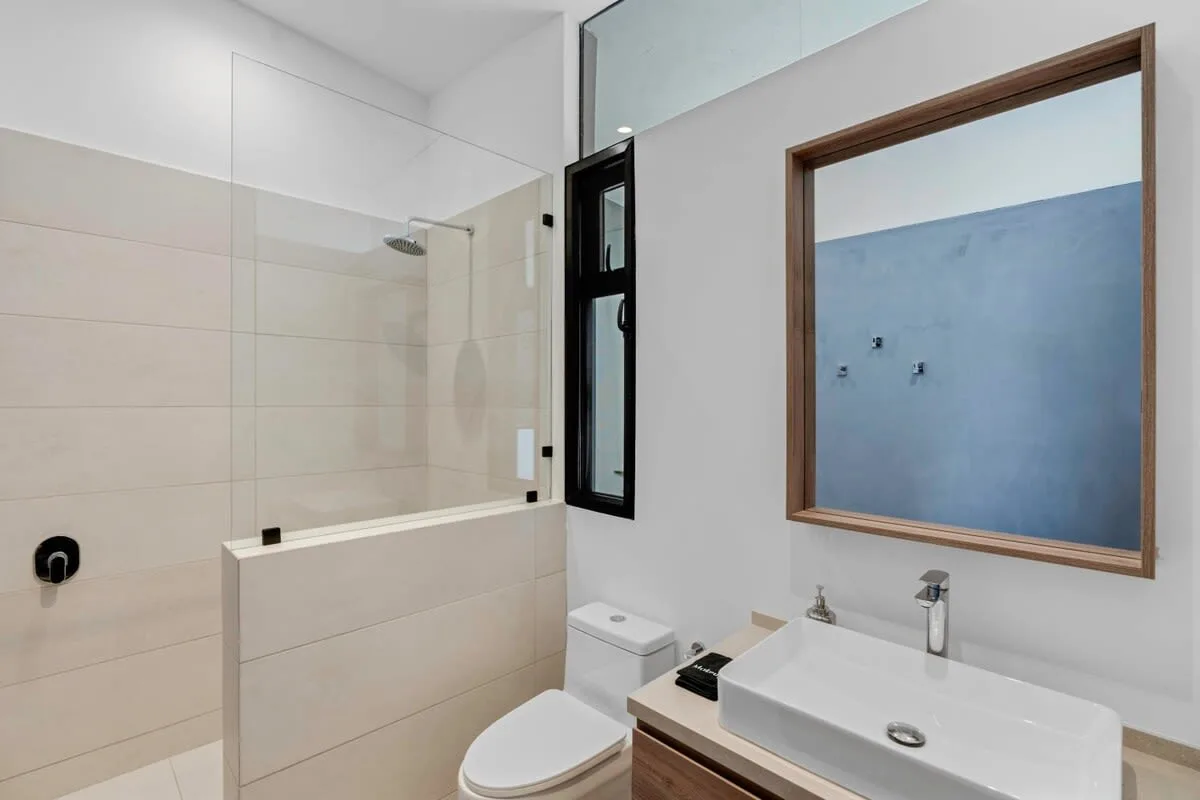 A modern bathroom with a glass shower, toilet, and sink.