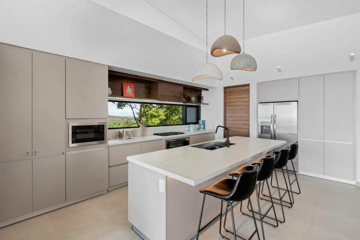 A modern kitchen with a large island and several stools.