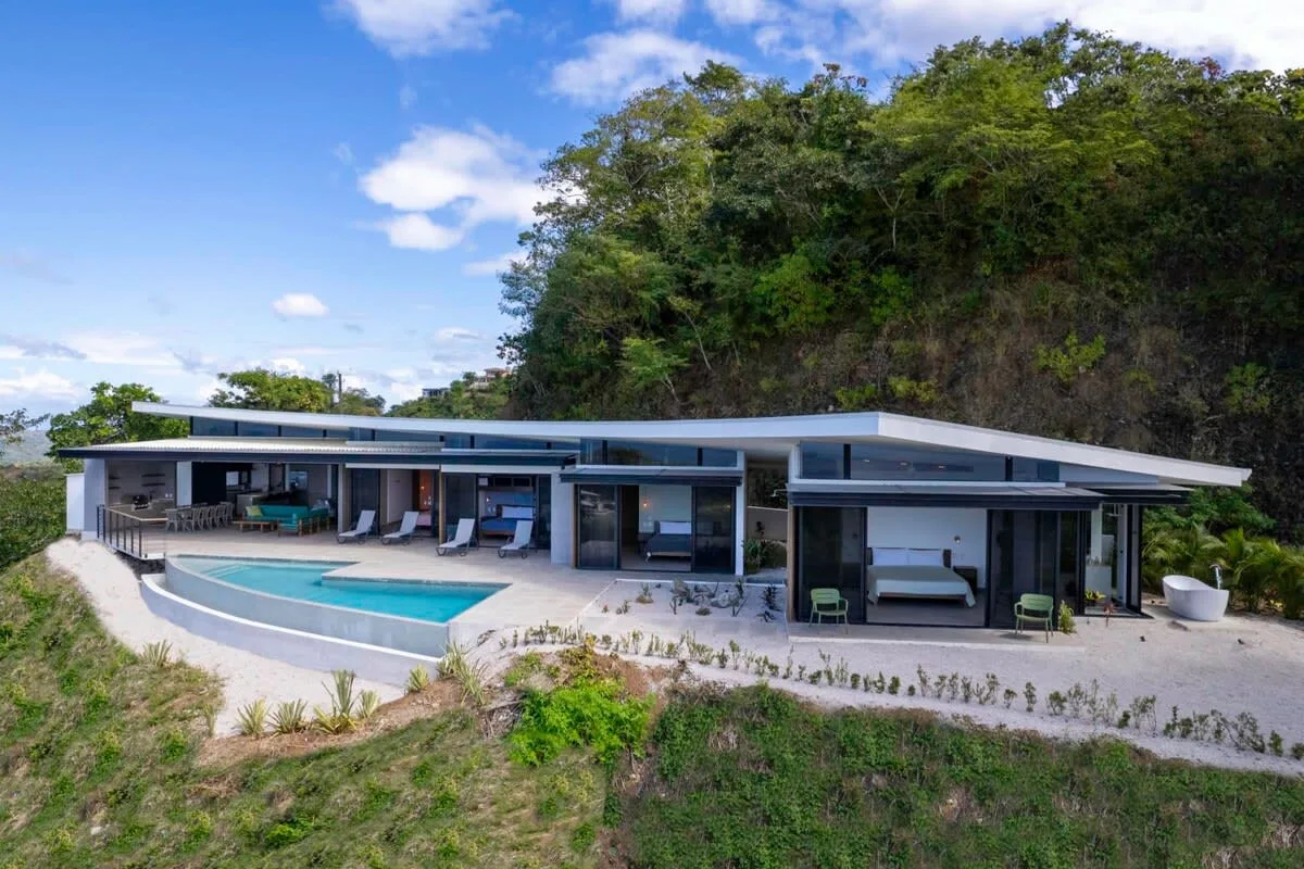 A modern low-rise building opens onto a terrace with a swimming pool.