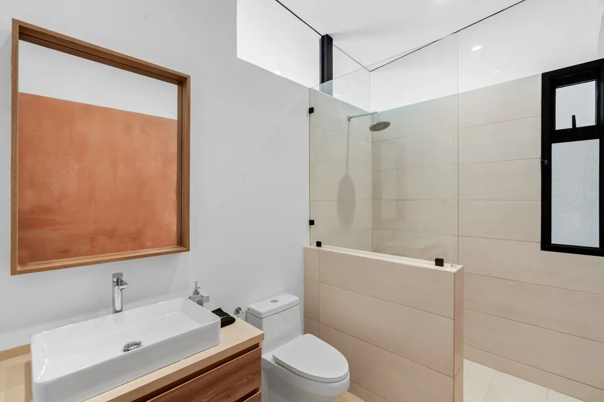 A modern bathroom with a sink, toilet, and glass shower area.